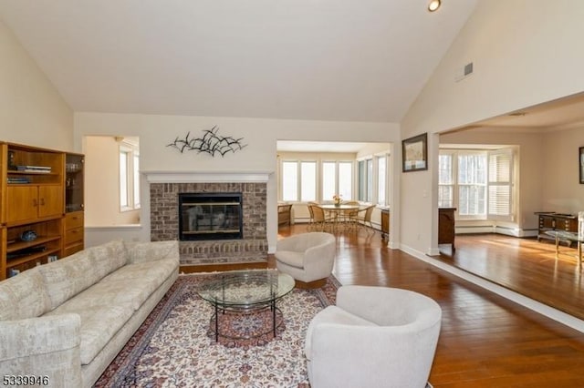 living room featuring a fireplace, visible vents, wood finished floors, high vaulted ceiling, and baseboards