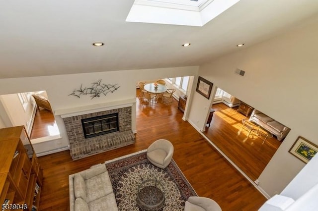 living area featuring a baseboard radiator, recessed lighting, a fireplace, dark wood-style floors, and lofted ceiling with skylight