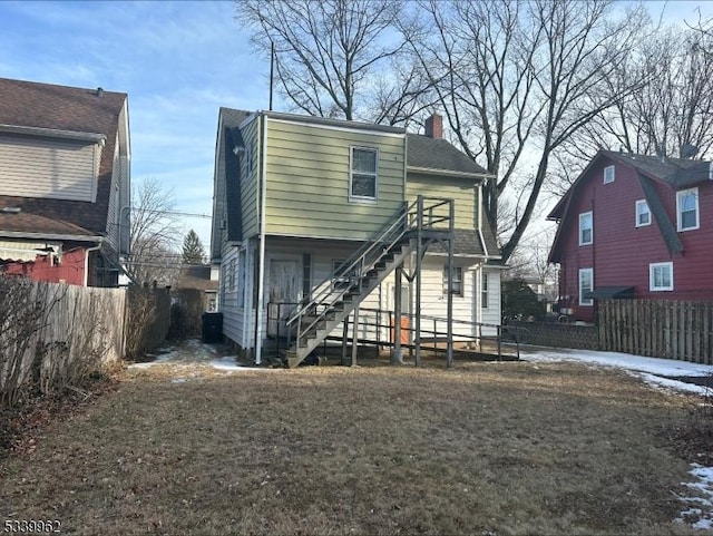 view of front facade featuring a chimney, stairs, and fence