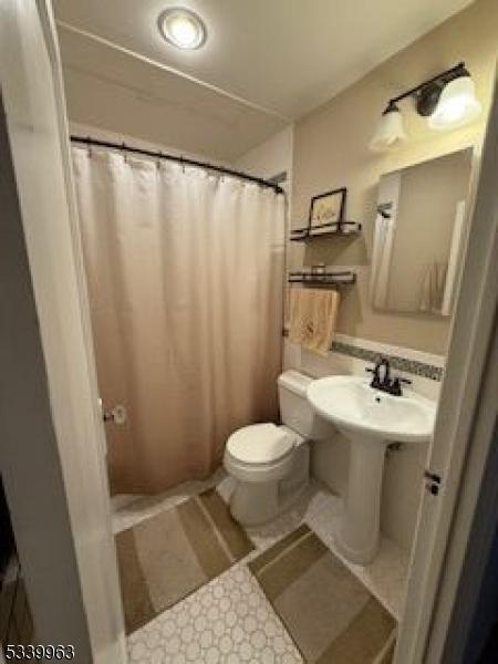 full bath featuring toilet and a shower with curtain