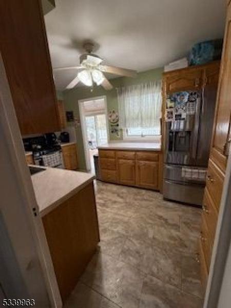 kitchen with stainless steel appliances, light countertops, a ceiling fan, and brown cabinets