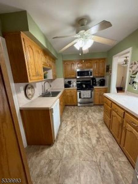 kitchen featuring ceiling fan, light countertops, appliances with stainless steel finishes, and a sink