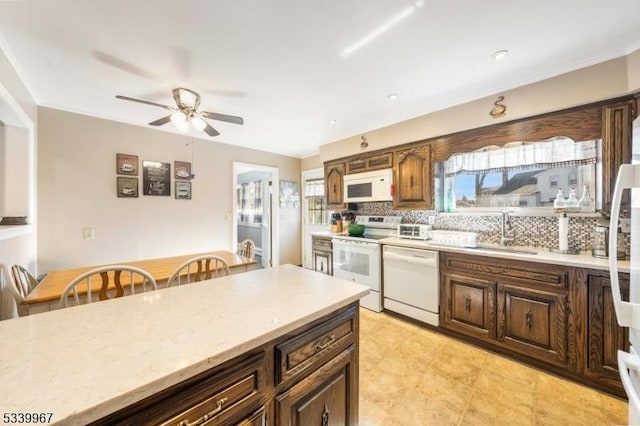 kitchen with white appliances, tasteful backsplash, light countertops, and a sink