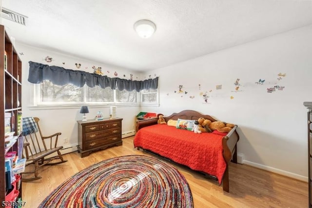 bedroom with light wood-type flooring, baseboards, visible vents, and baseboard heating