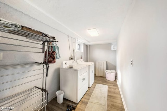 clothes washing area with laundry area, light wood-style flooring, baseboards, and separate washer and dryer