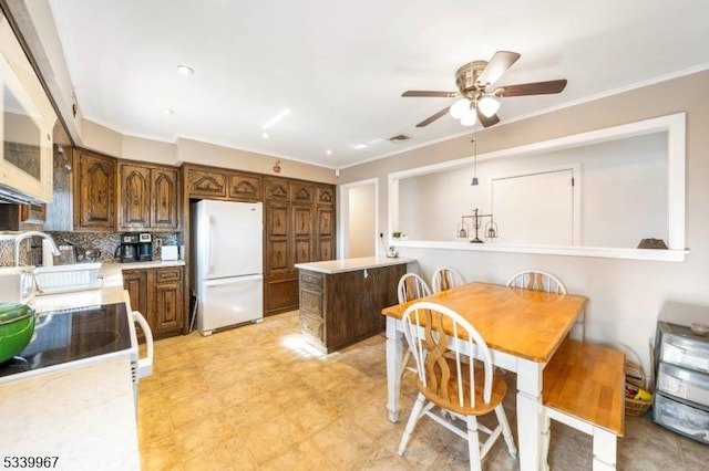 kitchen featuring decorative backsplash, a kitchen island, freestanding refrigerator, light countertops, and crown molding