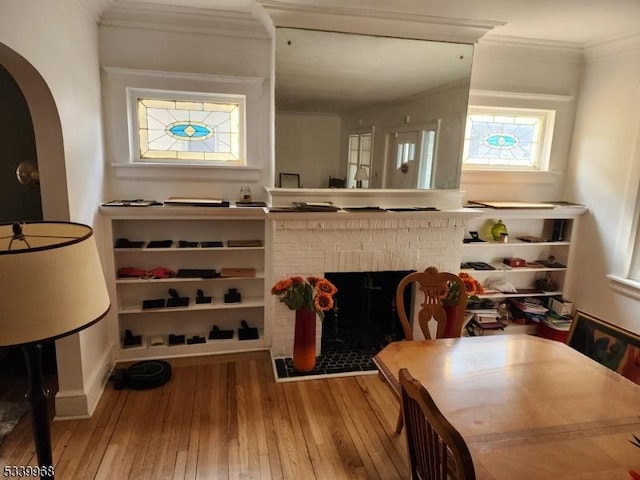 interior space with arched walkways, a fireplace, crown molding, and wood finished floors