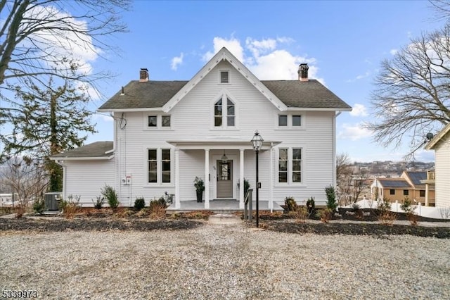 view of front facade with covered porch, a chimney, and cooling unit