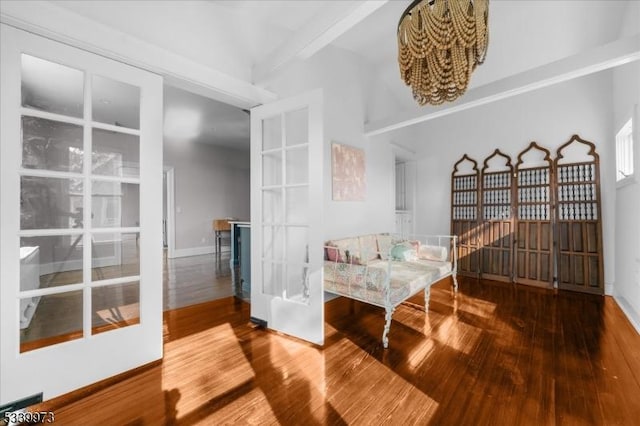 sitting room featuring beamed ceiling, baseboards, and wood finished floors