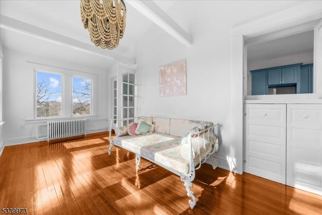 sitting room with radiator heating unit, baseboards, and wood-type flooring