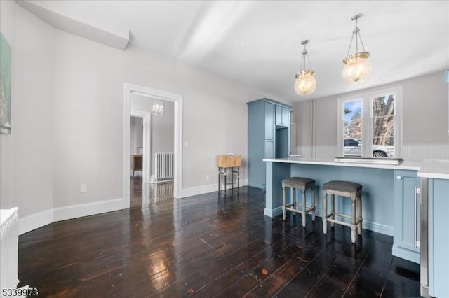 kitchen with dark wood-style floors, light countertops, blue cabinetry, a kitchen bar, and pendant lighting