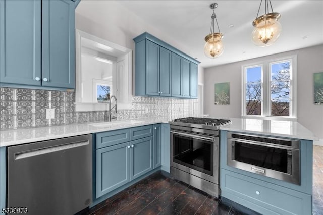 kitchen featuring stainless steel appliances, blue cabinets, a sink, and a peninsula