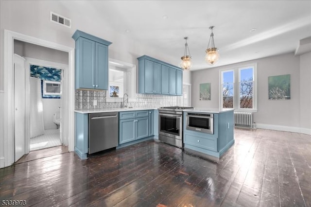 kitchen with visible vents, radiator heating unit, blue cabinets, stainless steel appliances, and a sink