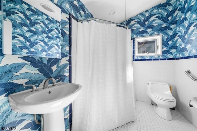 full bath with tile walls, a shower with curtain, toilet, tile patterned flooring, and wallpapered walls