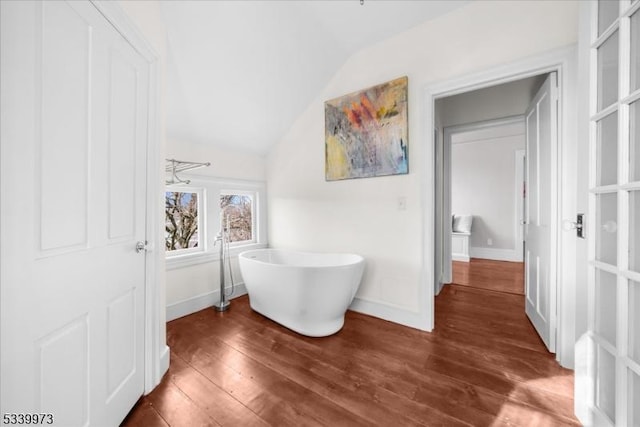 bathroom featuring lofted ceiling, a freestanding tub, baseboards, and wood finished floors