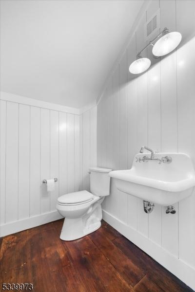 bathroom featuring visible vents, wood finished floors, toilet, and a decorative wall