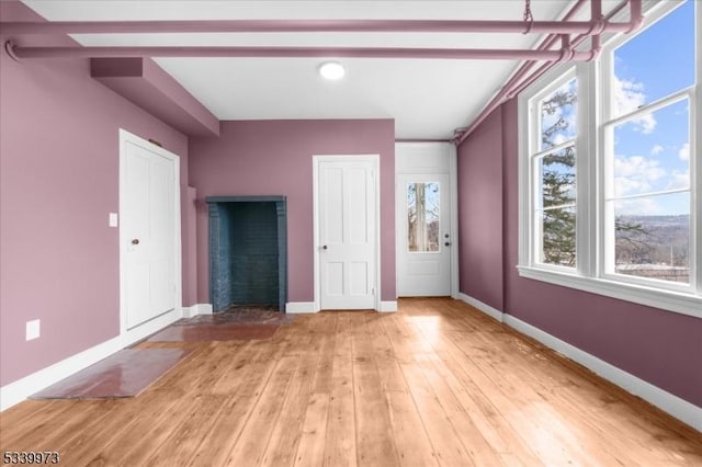 interior space featuring light wood-type flooring, beam ceiling, and baseboards