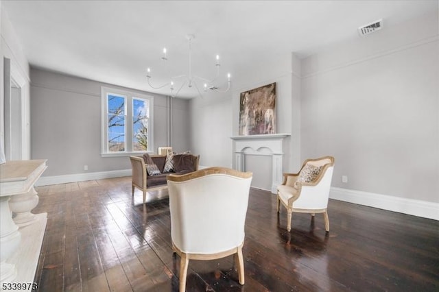 dining space featuring hardwood / wood-style flooring, a fireplace, visible vents, baseboards, and an inviting chandelier