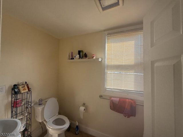 half bath with baseboards, visible vents, a sink, and toilet