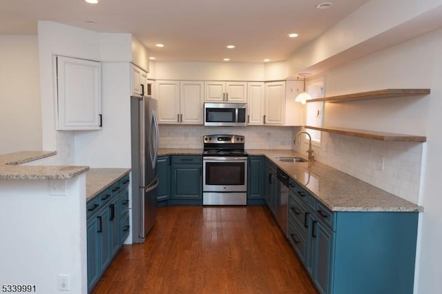 kitchen featuring dark wood-style floors, appliances with stainless steel finishes, light stone counters, blue cabinets, and a sink