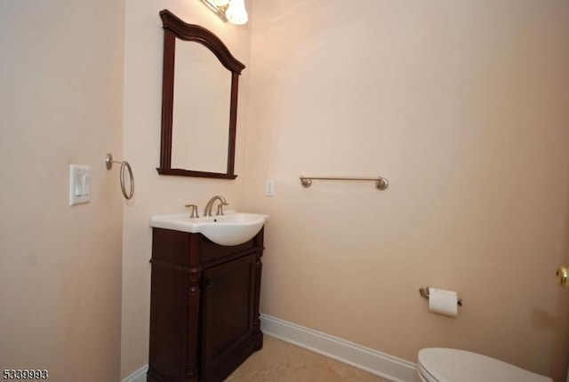 half bathroom featuring toilet, vanity, and baseboards