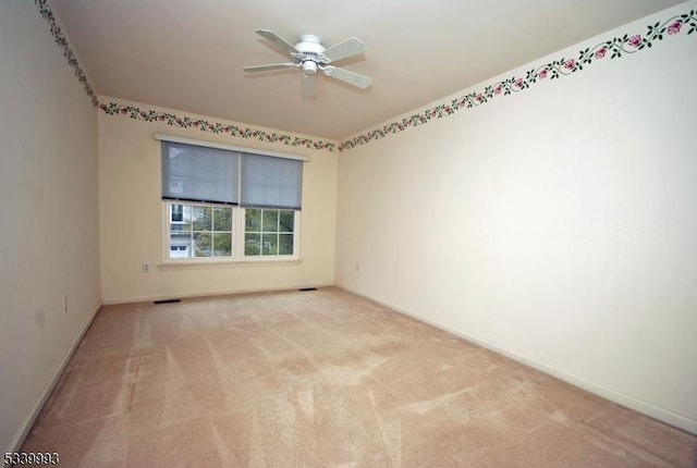 carpeted spare room featuring visible vents, ceiling fan, and baseboards