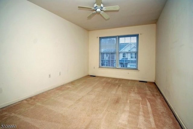 empty room featuring light carpet, ceiling fan, and baseboards