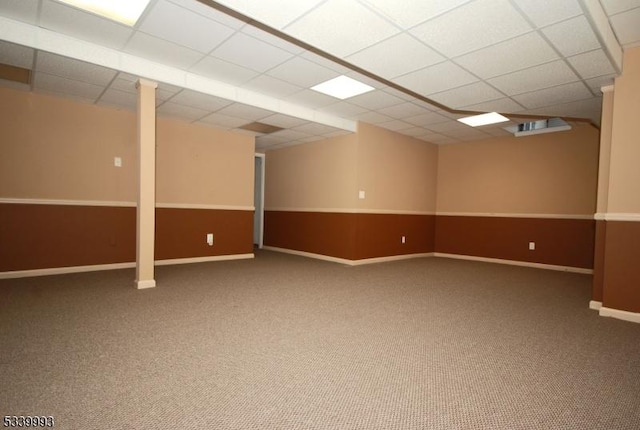 finished below grade area featuring a paneled ceiling, baseboards, and carpet floors