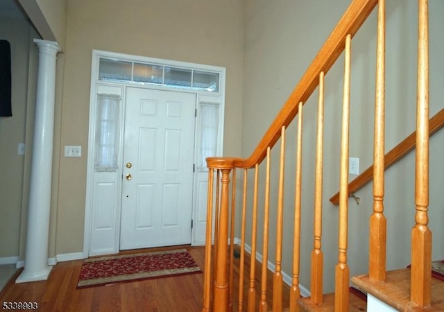 foyer entrance with decorative columns, stairway, baseboards, and wood finished floors