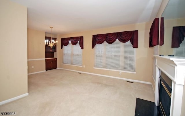 unfurnished living room with a fireplace with flush hearth, visible vents, baseboards, carpet, and an inviting chandelier