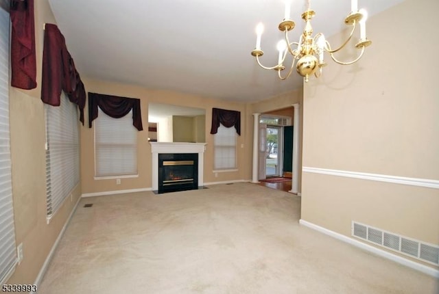 unfurnished living room with a notable chandelier, a fireplace with flush hearth, visible vents, baseboards, and carpet