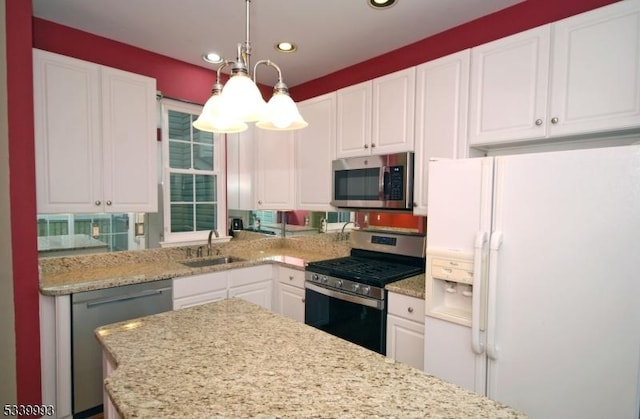 kitchen featuring recessed lighting, a sink, white cabinets, appliances with stainless steel finishes, and decorative light fixtures