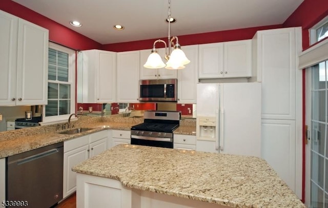 kitchen with light stone countertops, white cabinetry, stainless steel appliances, and a sink