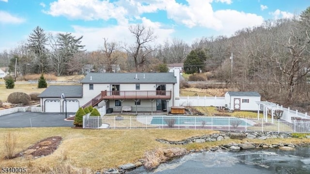 back of house featuring an outbuilding, a wooden deck, a fenced backyard, stairs, and a lawn