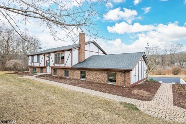 view of property exterior featuring a lawn, brick siding, roof with shingles, and a chimney