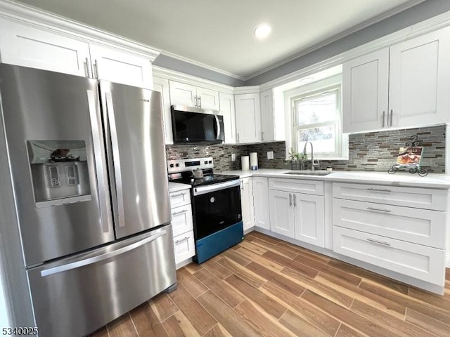 kitchen with stainless steel appliances, a sink, white cabinets, light countertops, and backsplash