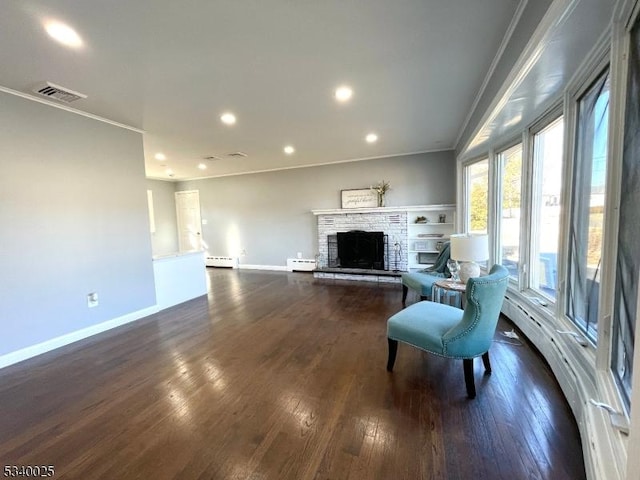 living area featuring a fireplace, visible vents, baseboard heating, dark wood-style floors, and crown molding