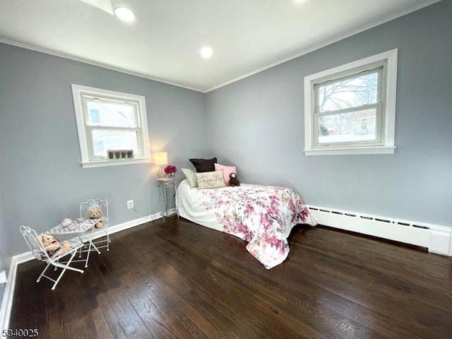 bedroom featuring a baseboard heating unit, hardwood / wood-style floors, ornamental molding, and baseboards