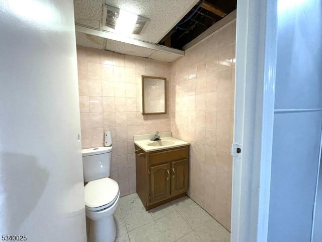 bathroom featuring tile walls, vanity, toilet, and tile patterned floors