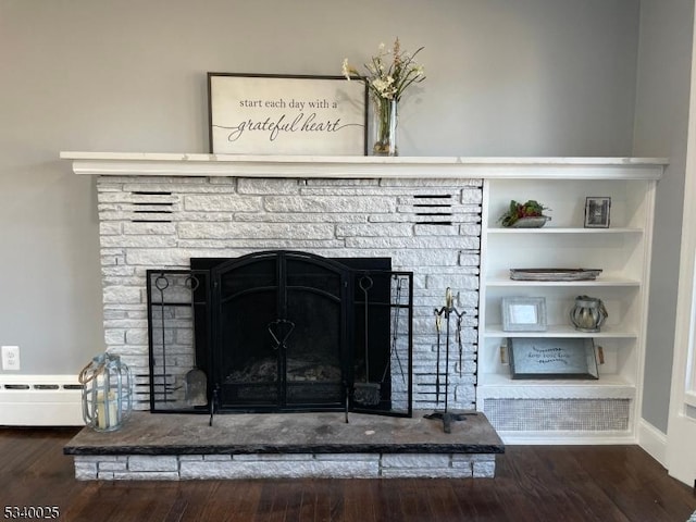 room details with built in shelves, baseboards, wood finished floors, and a stone fireplace