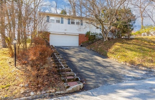 view of front of house with an attached garage, aphalt driveway, and brick siding