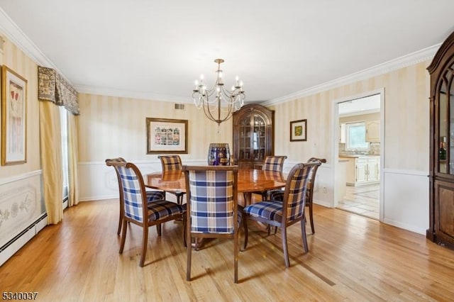 dining area with a baseboard heating unit, light wood-style flooring, and ornamental molding