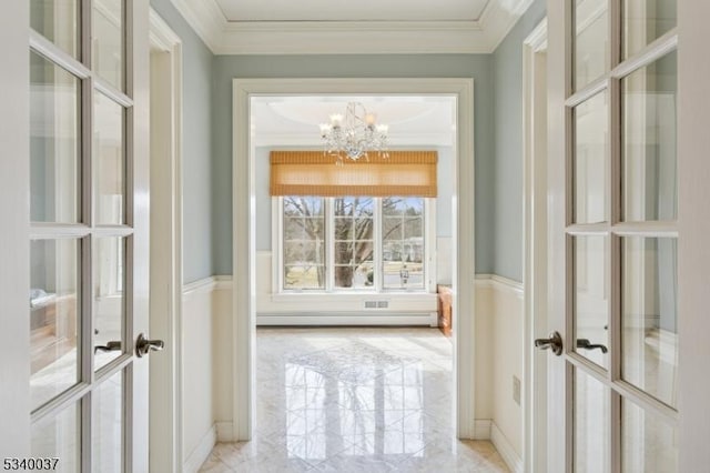 corridor with a baseboard heating unit, crown molding, french doors, a notable chandelier, and marble finish floor