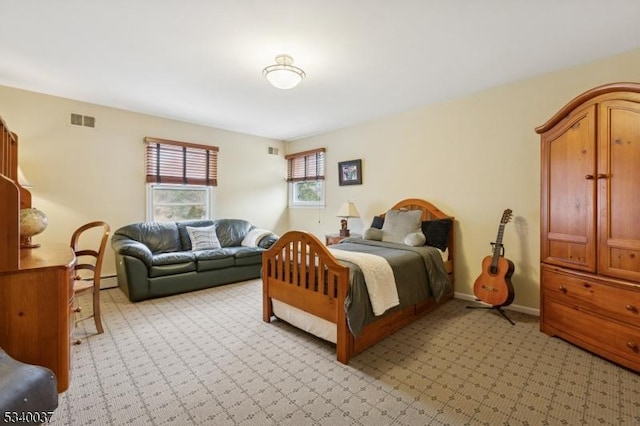 bedroom featuring a baseboard heating unit, light colored carpet, visible vents, and baseboards