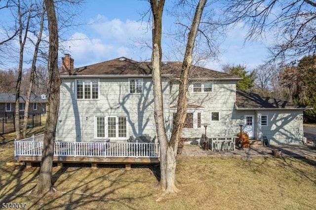 rear view of house featuring a lawn, a chimney, and a deck