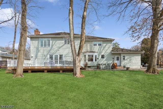 rear view of property featuring a wooden deck, a yard, and a chimney