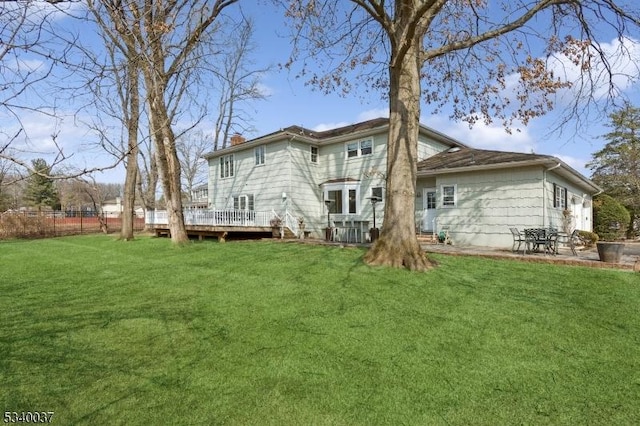 back of house with a wooden deck, a chimney, and a yard