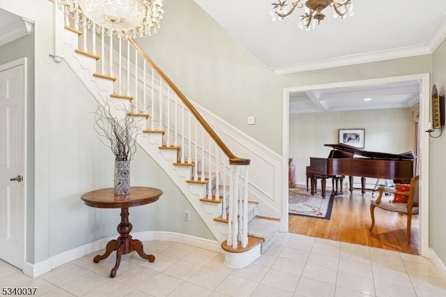 staircase with an inviting chandelier, crown molding, baseboards, and tile patterned floors