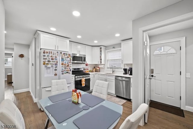 kitchen with wood finished floors, a sink, white cabinets, light countertops, and appliances with stainless steel finishes