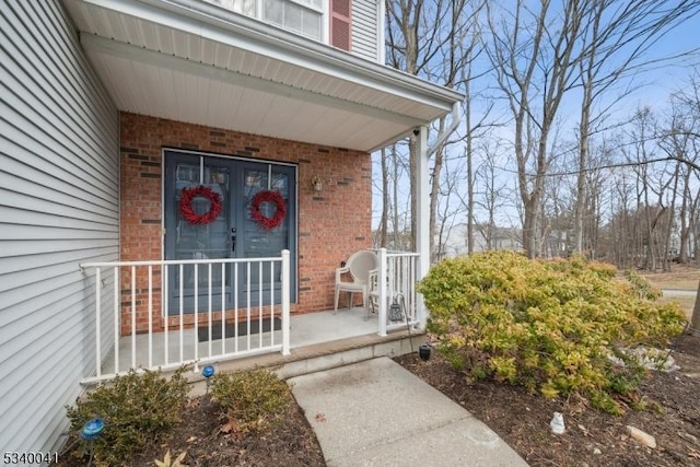 view of exterior entry featuring covered porch and brick siding